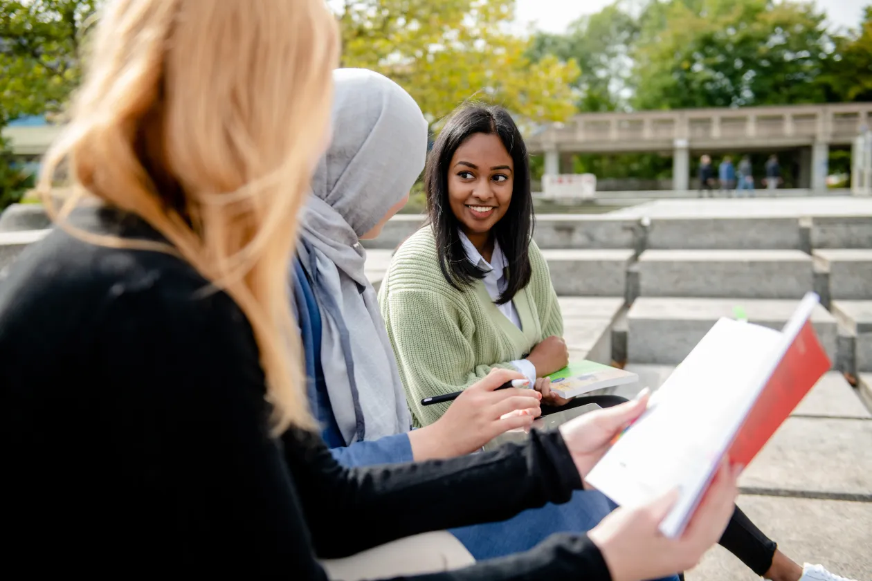 Drei Studentinnen sitzen auf dem Campus