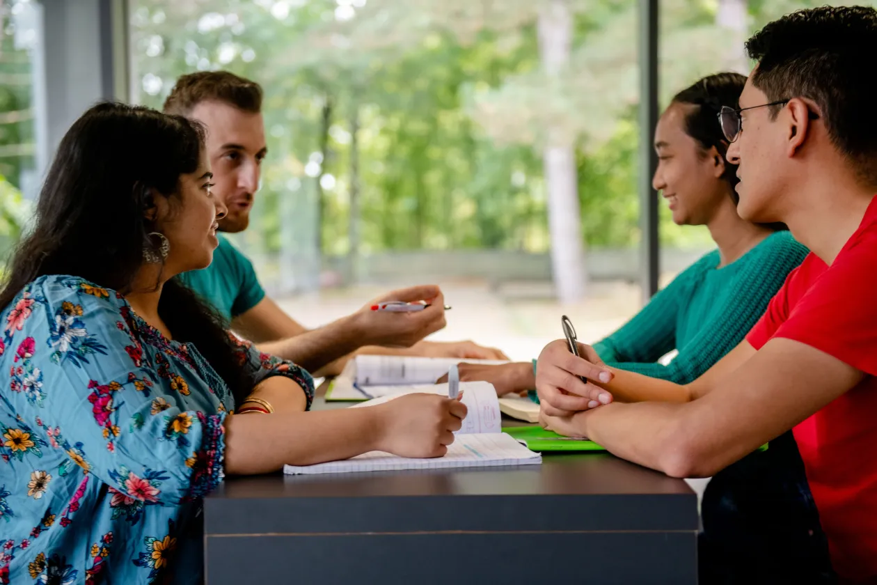 Gruppe Studierender sitzt am Tisch und unterhält sich