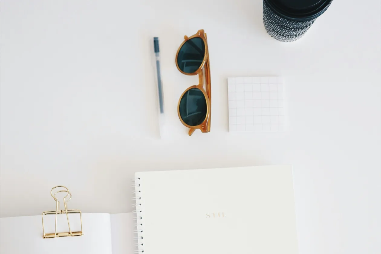 Hefte, Stift und Sonnenbrille auf Tisch