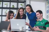 Vier Studierende am Tisch schauen auf Laptop