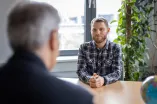Bewerbungsgespräch in dem den Hinterkopf eines Mannes und am anderen Seite des Tisches einen Bewerber sitzt