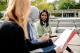 Drei Studentinnen sitzen auf dem Campus
