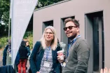 Two Panelists speaking to another at a coffee break, one has a coffee mug in his hand