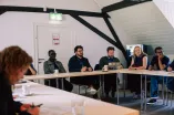 Workshop participants sitting at tables in a square setting