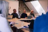 Workshop participants sitting at tables in a square setting