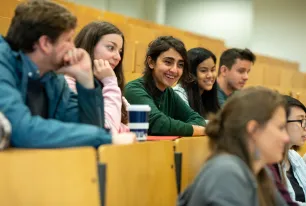 Gruppe von Studierenden lachend in einem Hörsaal.
