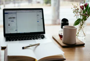 Schreibtisch mit Laptop, Kaffee und Notizbuch