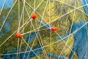 Das Bild zeigt einen Globus mit Pins, welche mit Fäden verbunden sind.