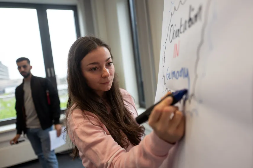 Studierende schreibt auf Whiteboard