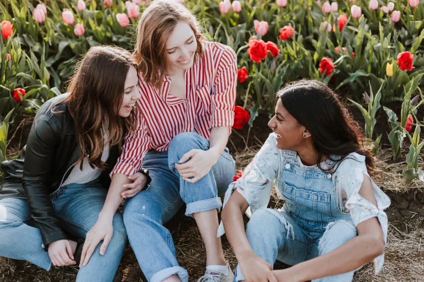 Three women sitting near flowers