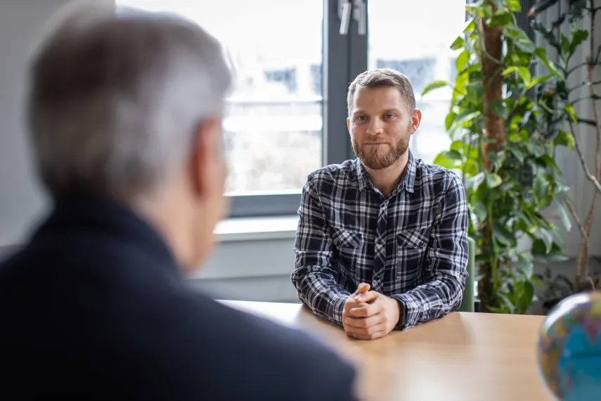 Bewerbungsgespräch in dem den Hinterkopf eines Mannes und am anderen Seite des Tisches einen Bewerber sitzt
