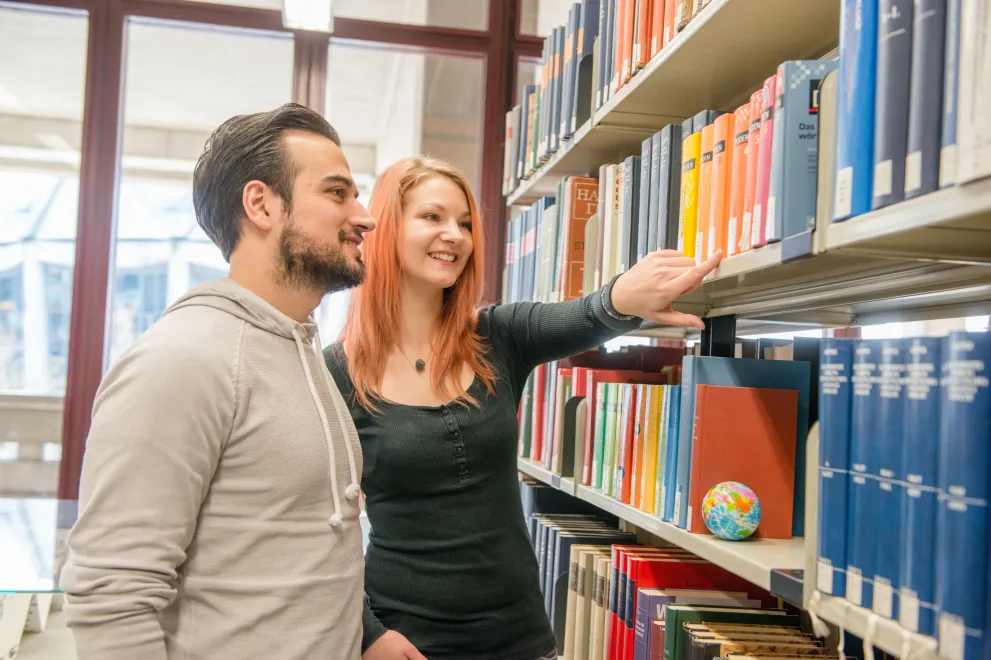 zwei Studierende suchen gemeinsam ein Buch aus