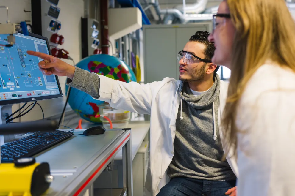 Wissenschaftler:in gucken auf einen Bildschirm im Labor