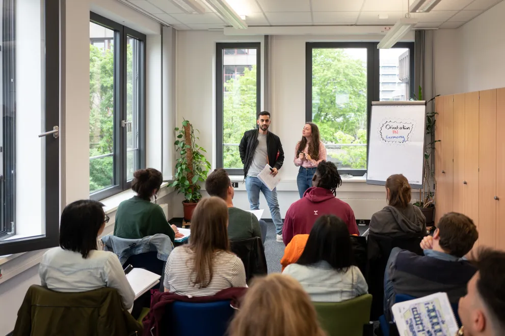 zwei Vortragende und eine Gruppe von Studierenden die ihnen zuhören 