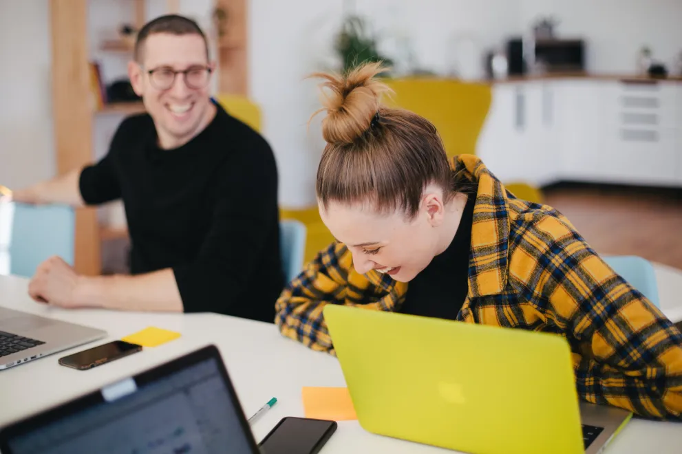 Zwei Personen lachend mit Laptop