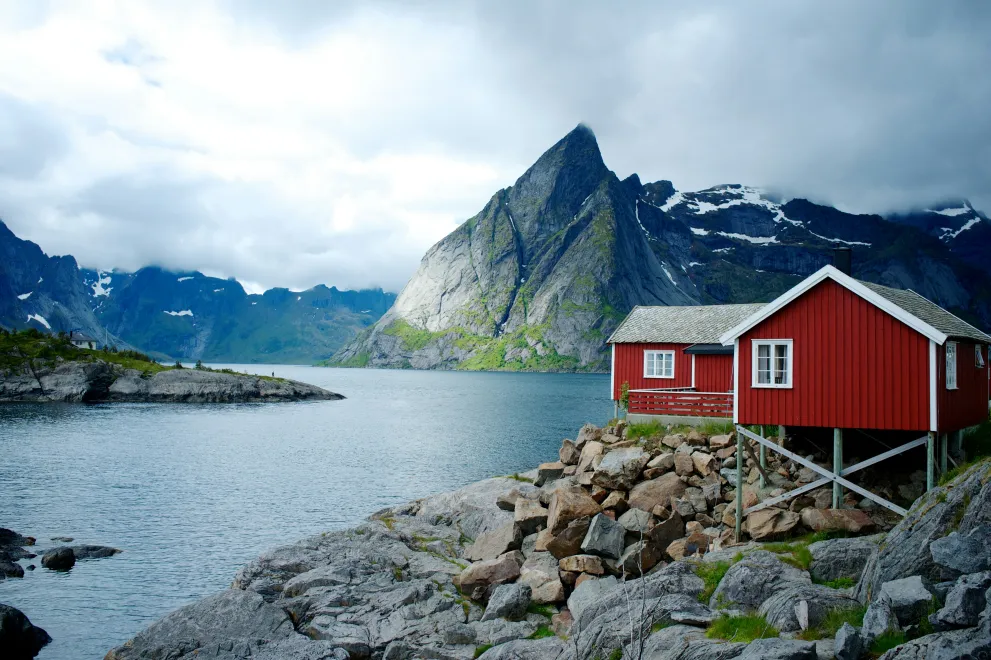 Norwegischer Fjord mit Bergen und einem roten Holzhaus