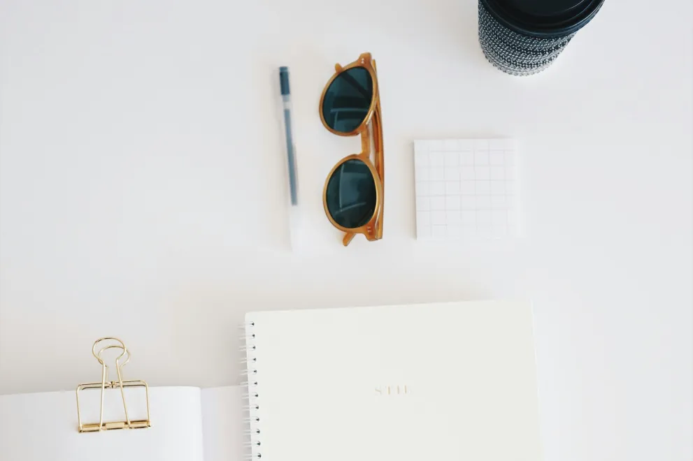 Hefte, Stift und Sonnenbrille auf Tisch