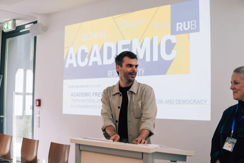 Panelist in front of a presentation about the Academic Freedom Forum