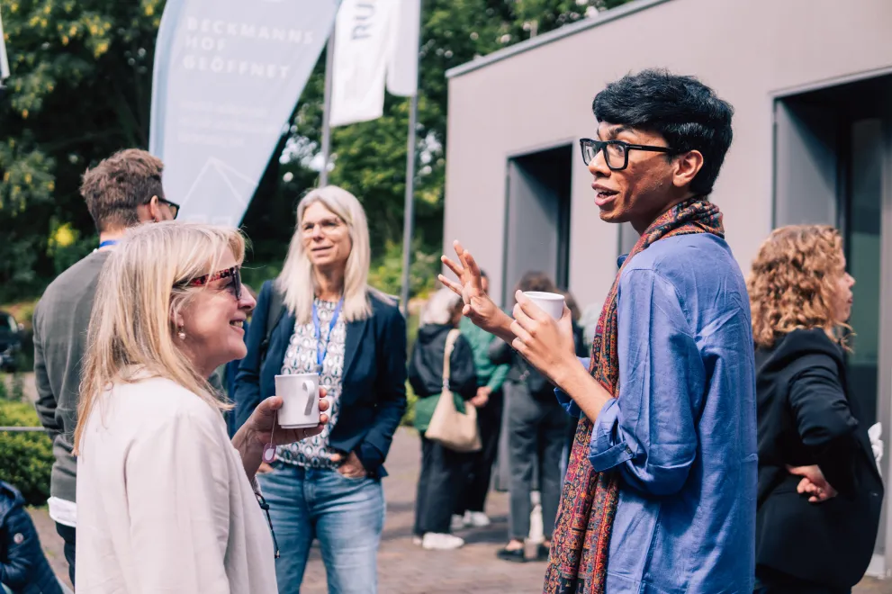 Participants of the Academic Freedom Forum speaking to each other during a coffee break, coffee mugs in hand
