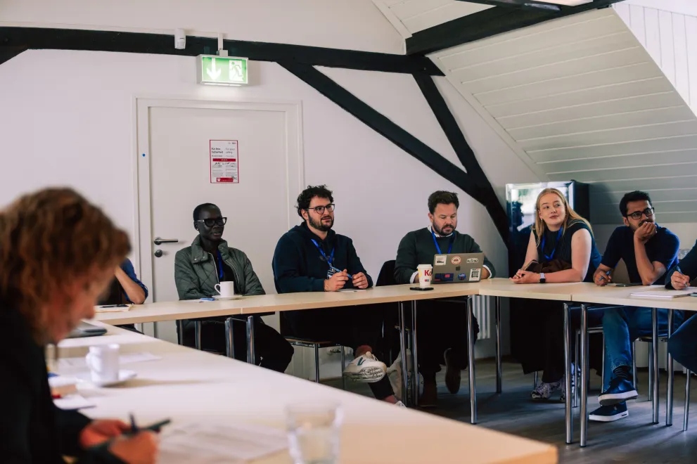 Workshop participants sitting at tables in a square setting