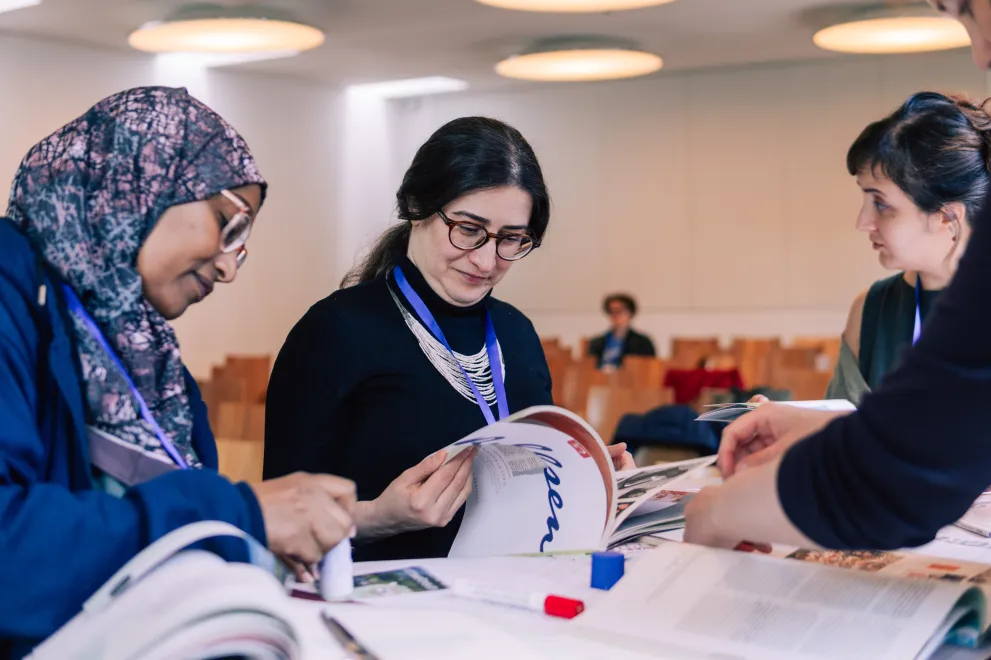 Three women are flipping through magazines at one of the Working Group Sessions.