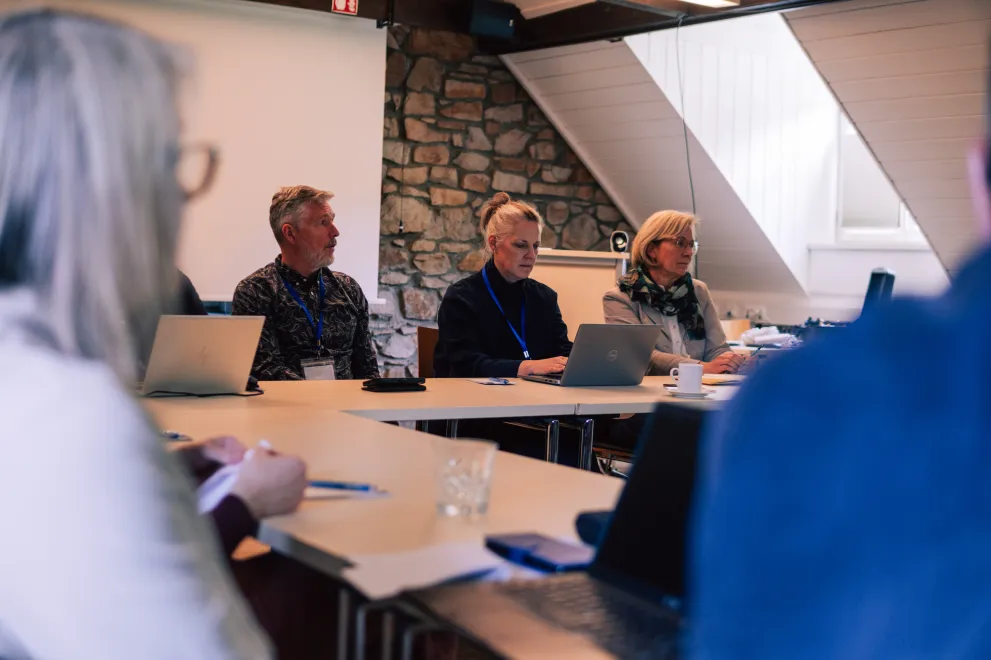 Workshop participants sitting at tables in a square setting