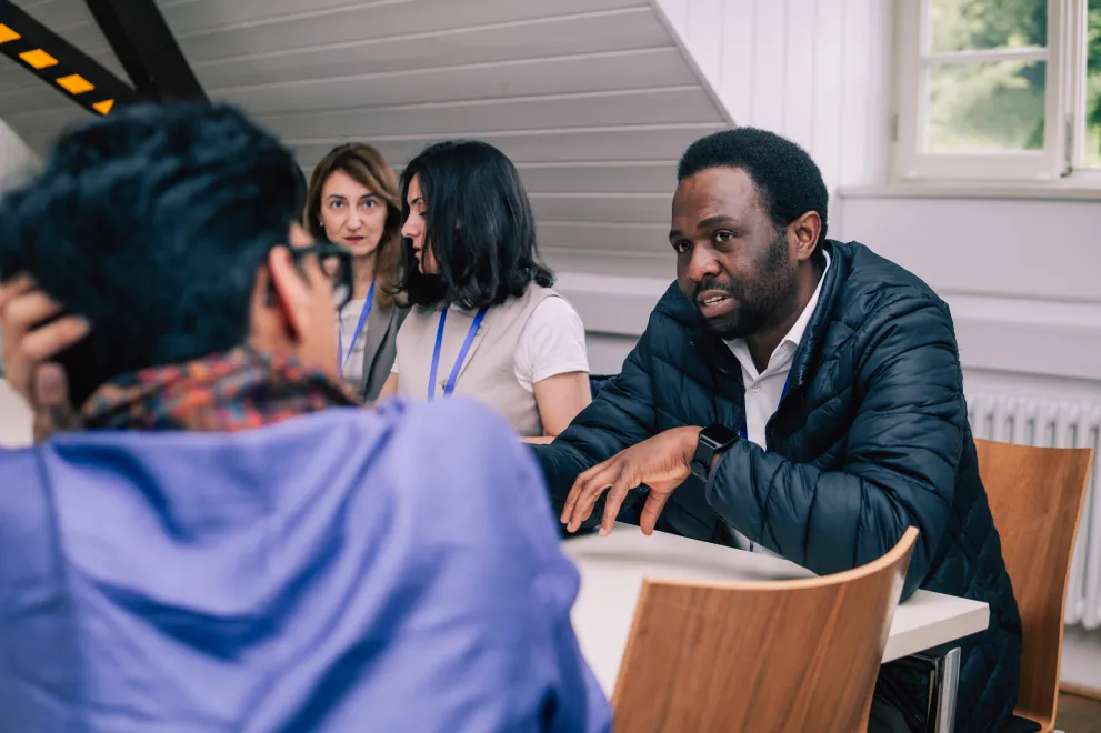 Participents of a workshop sitting on tables and talking to each other